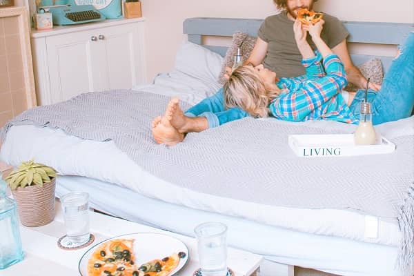 ベッドの上でイチャイチャピザを食べるカップル