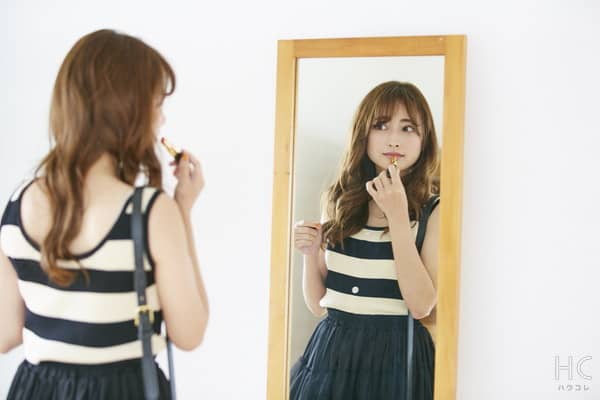 鏡を見て化粧する女性
